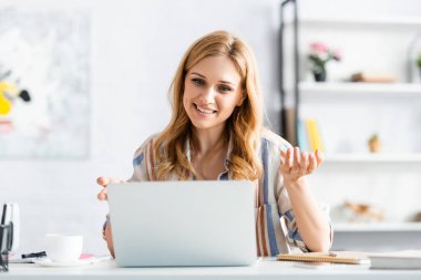  Selective focus of woman smiling and talking during webinar  clipart