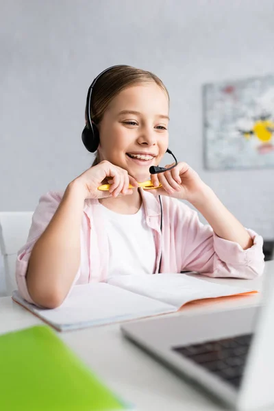 Selective Focus Smiling Child Headset Holding Pen Looking Laptop Table — Stock Photo, Image