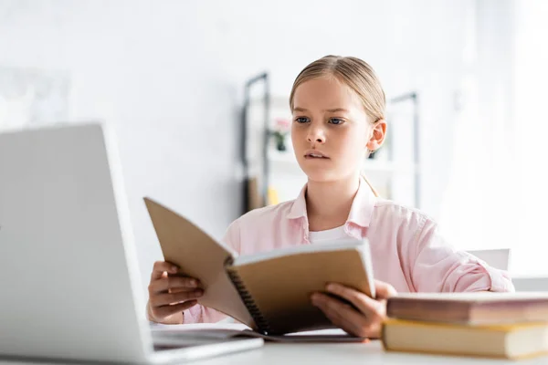 Selective Focus Concentrated Kid Looking Laptop While Holding Notebook Table — Stock Photo, Image