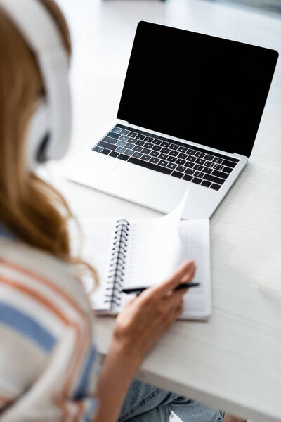 Cropped view of woman working with notebook and laptop 