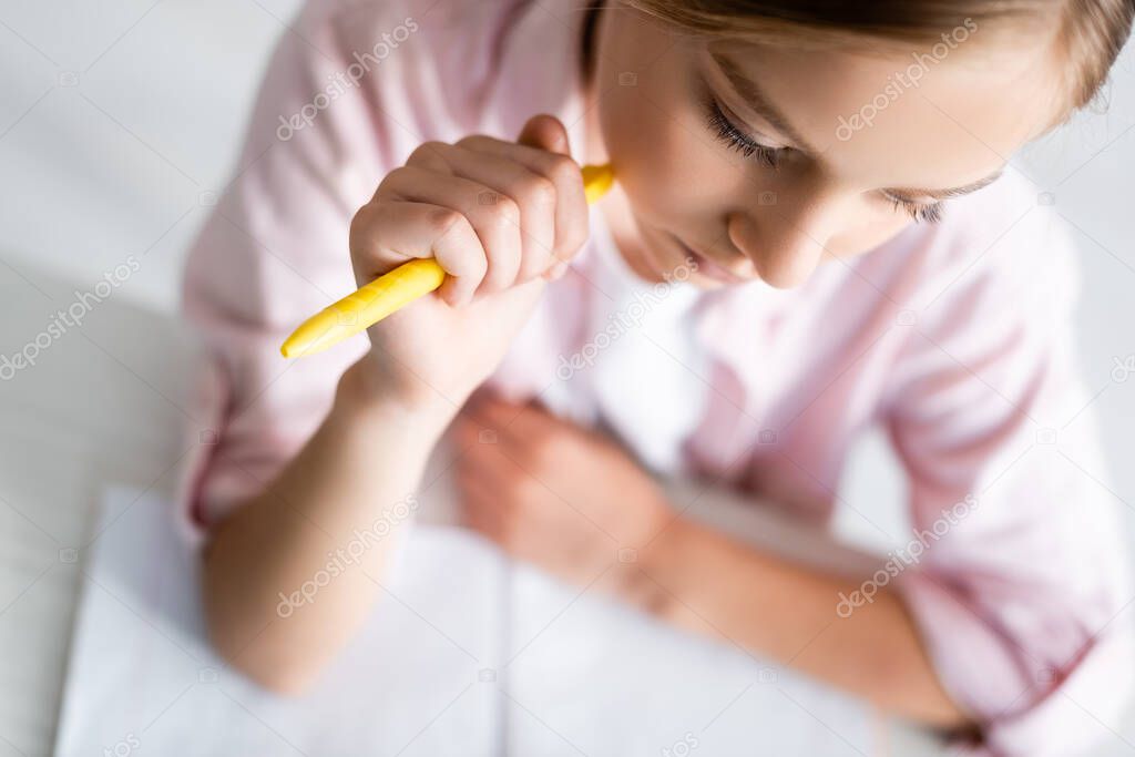 Overhead view of kid holding pen near copy book on table on grey background