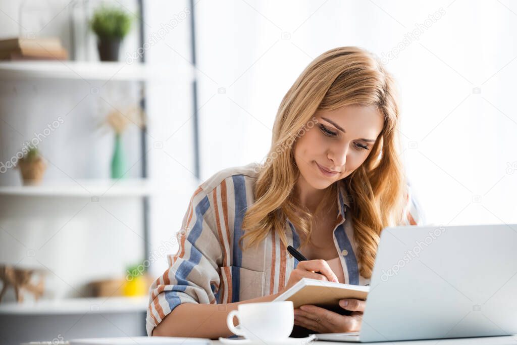 Selective focus of pretty focused woman writing notebook