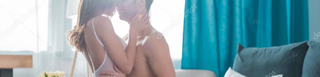 Panoramic orientation of woman kissing shirtless boyfriend in bedroom