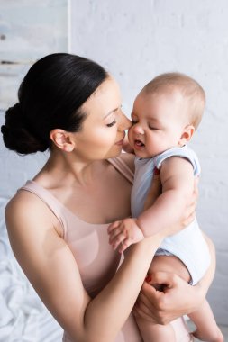 Çekici anne, bebek arabasındaki bebeğe bakıyor. 