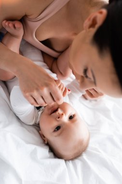 Annenin bebeğe yatakta dokunduğu seçici odak noktası.