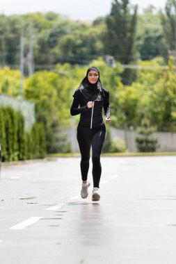 müslüman sporcu kadın tesettür ve spor kıyafetleri içinde dışarıda koşuyor.