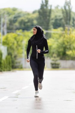 Genç Müslüman spor kadın tesettür ve spor kıyafetleri içinde dışarıda koşuyor.