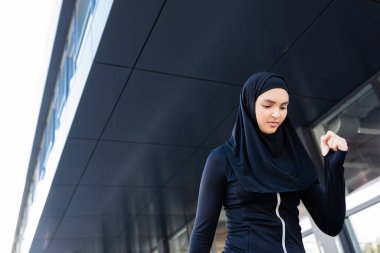 Binanın yakınında siyah tesettürlü Müslüman sporcu kadın 