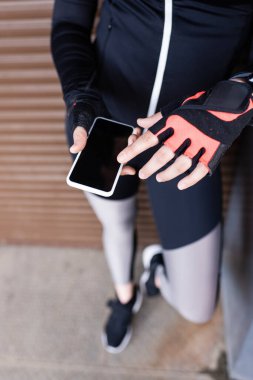 Kesilmiş spor kadın görüntüsü boş ekran ile akıllı telefon tutuyor