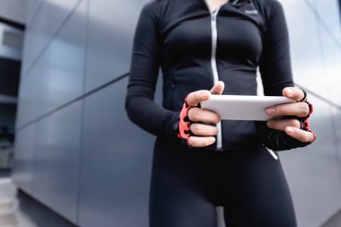 Spor giyim bölümünde elinde akıllı telefon olan bir kadın. 