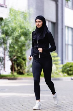 Dışarıda koşan tesettürlü ve spor giysili genç Arap sporcu. 