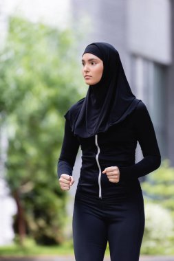 Genç Arap sporcu kadın tesettür ve spor kıyafetleri içinde dışarıda koşuyor. 
