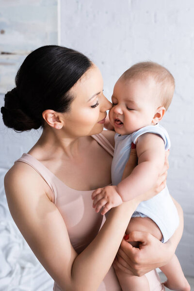 attractive mother looking at infant son in baby romper 