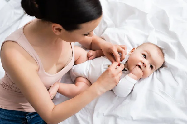 Frau Berührt Entzückenden Sohn Babystrampler Mit Fliege Auf Bett Liegend — Stockfoto