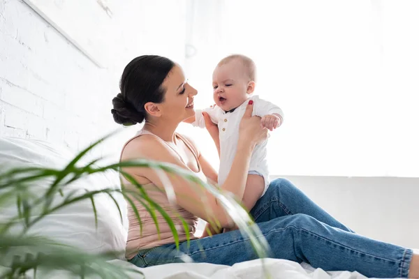 Enfoque Selectivo Mujer Feliz Jeans Sentados Cama Sosteniendo Brazos Lindo —  Fotos de Stock