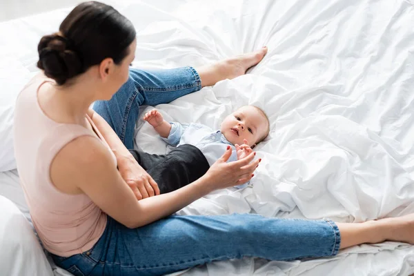 Overhead View Mother Jeans Sitting Bed Touching Cute Infant Son — Stock Photo, Image