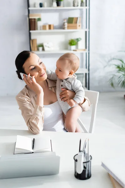 Selective Focus Attractive Freelancer Holding Arms Infant Son Talking Smartphone — Stock Photo, Image