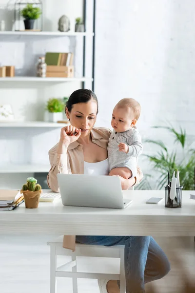 Mãe Segurando Nos Braços Filho Bebê Olhando Para Laptop Casa — Fotografia de Stock