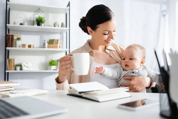 Selective Focus Happy Woman Holding Cup Cute Infant Son Gadgets — Stock Photo, Image