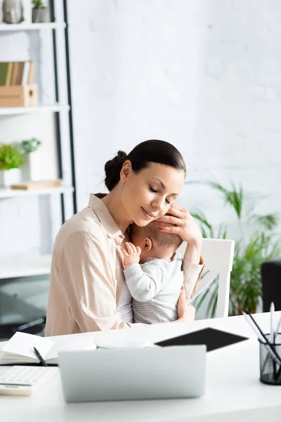 Mother Closed Eyes Hugging Baby Boy Gadgets Table — Stock Photo, Image