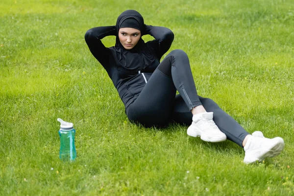 Mladá Muslimka Sportovkyně Hidžábu Cvičení Trávě Blízkosti Sportovní Láhev Vodou — Stock fotografie