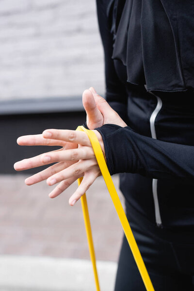 cropped view of sportswoman exercising with resistance band