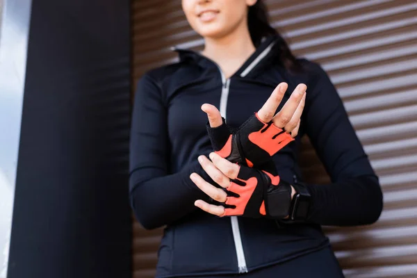 立ってスポーツ手袋に触れる若い女性のクロップドビュー — ストック写真