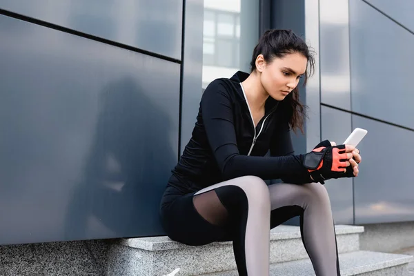 Ung Idrottskvinna Sitter Och Använder Smartphone Utanför — Stockfoto