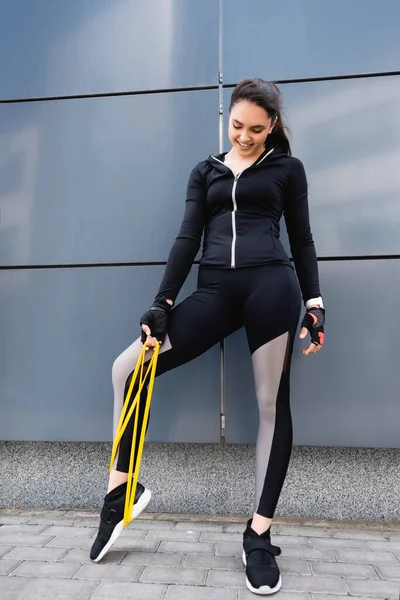 Sonriente Joven Deportista Haciendo Ejercicio Con Banda Resistencia Cerca Construcción — Foto de Stock