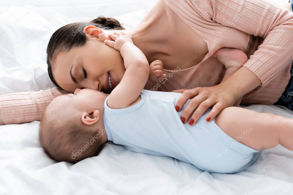 mother with closed eyes lying on bed with baby boy 