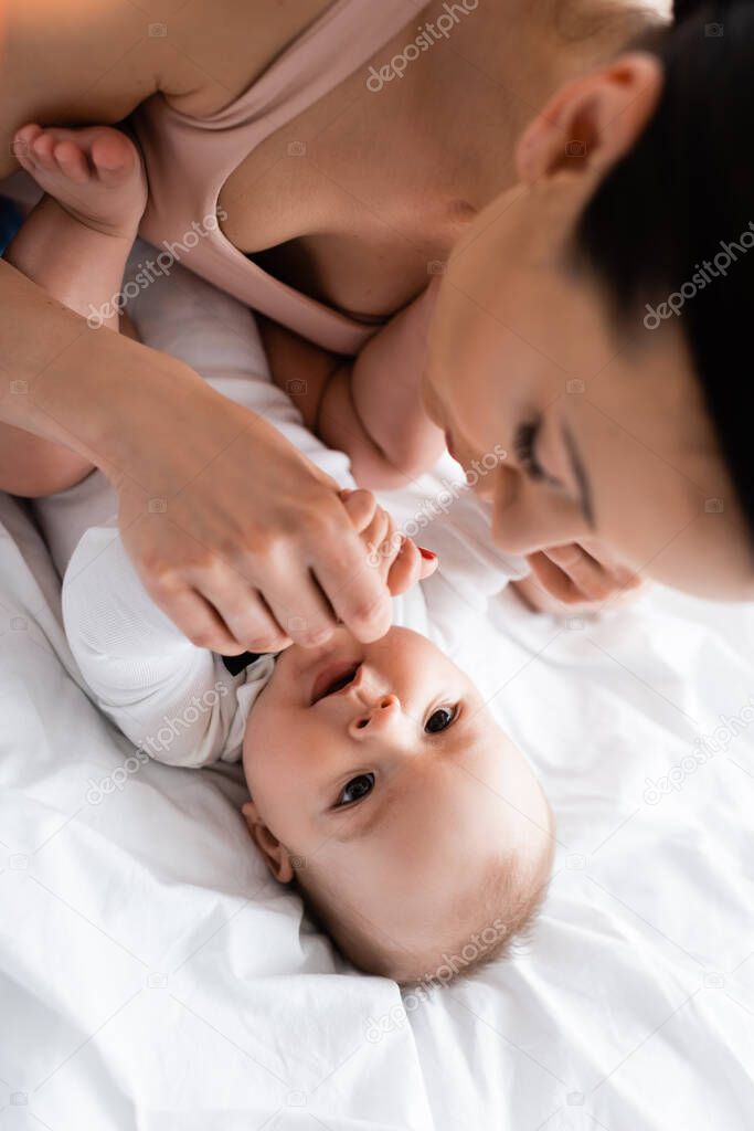 selective focus of mother touching infant son on bed