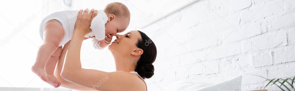 panoramic concept of happy mother holding in arms cute infant son in bedroom 