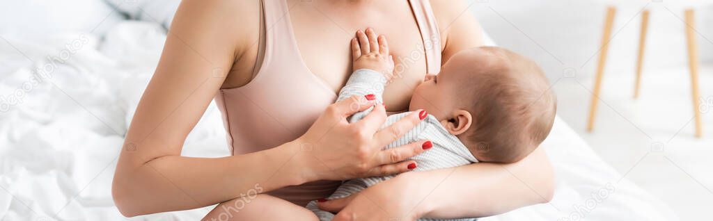 panoramic crop of caring mother breastfeeding baby boy in bedroom 