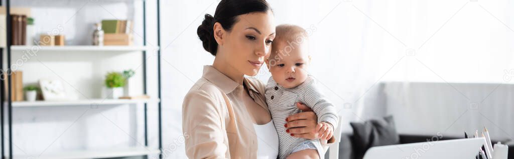 website header of mother holding in arms baby boy 