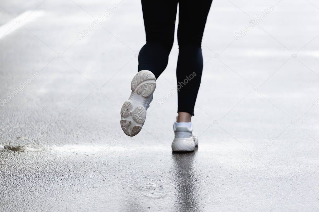 cropped view of sportswoman in sneakers running outside 