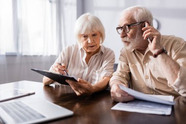 Üst düzey bir adamın akıllı telefondan belgeli eşinin yanında konuşmasının seçici odak noktası  