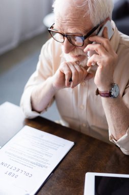 Son sınıf öğrencisi akıllı telefondan kağıtların yanında borç tahsilatı mektupları ve dijital tabletle konuşuyor. 