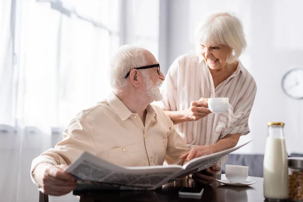 Enfoque Selectivo Del Anciano Sosteniendo Periódico Sonriendo Esposa Con Una — Foto de Stock