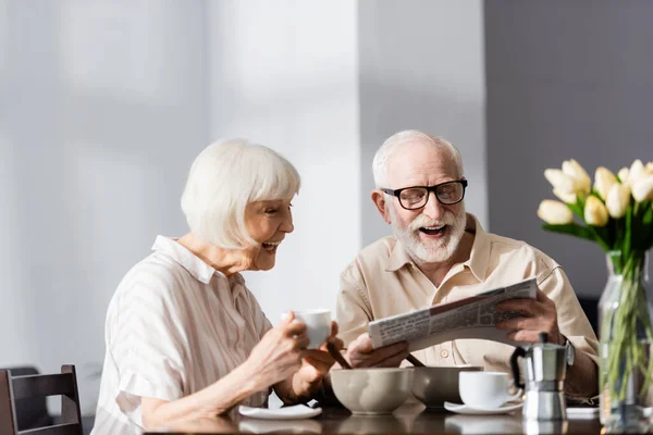 Selective Focus Cheerful Senior Couple Reading Newspaper Breakfast Kitchen — Stock Photo, Image