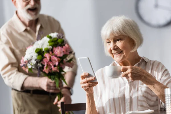 Selective Focus Smiling Woman Holding Cup Coffee Using Smartphone Husband — Stock Photo, Image