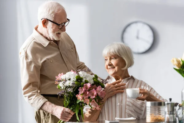 Selective Focus Elderly Man Giving Bouquet Positive Wife Cup Coffee — Stock Photo, Image