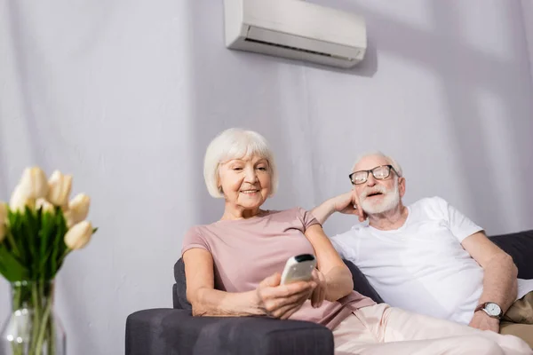 Focus Selettivo Della Donna Anziana Sorridente Con Telecomando Del Condizionatore — Foto Stock