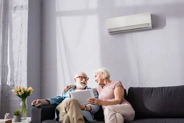 Mujer Mayor Sosteniendo Tableta Digital Mirando Sonriente Marido Sosteniendo Controlador — Foto de Stock