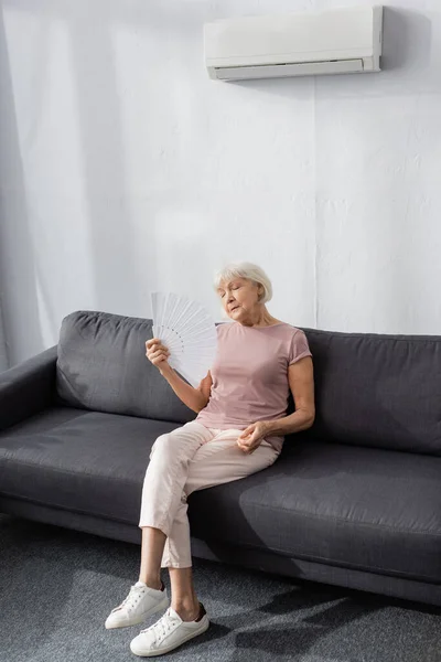 Ältere Frau Hält Ventilator Während Hitze Auf Sofa — Stockfoto