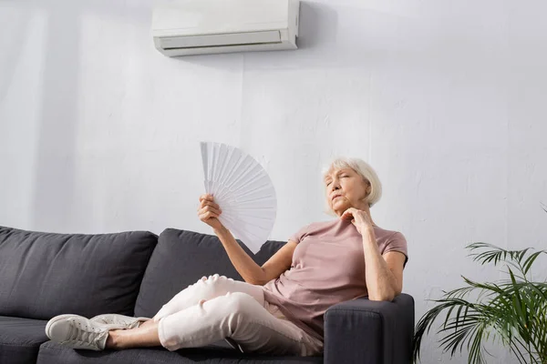 Selective Focus Elderly Woman Waving Fan While Sitting Couch Living — Stock Photo, Image
