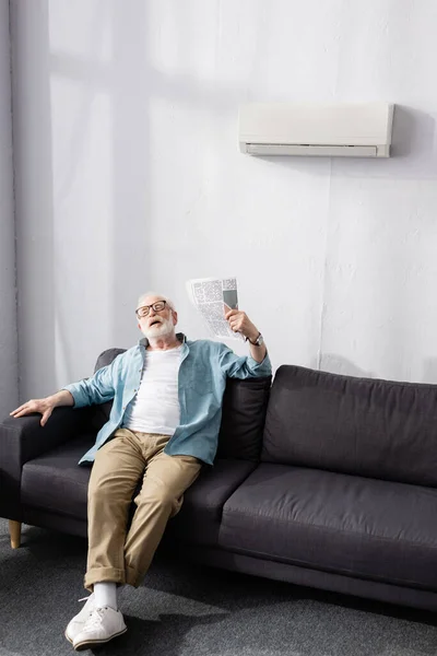 Hombre Mayor Agitando Periódico Mientras Sufre Calor Sofá — Foto de Stock