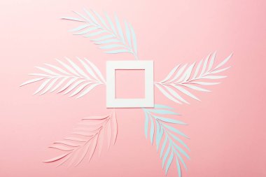 top view of white, pink and blue paper cut palm leaves and square frame on pink background clipart