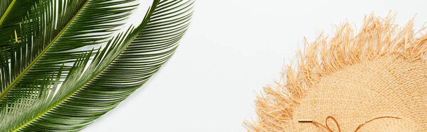 top view of green palm leaves near straw hat on white background, panoramic shot