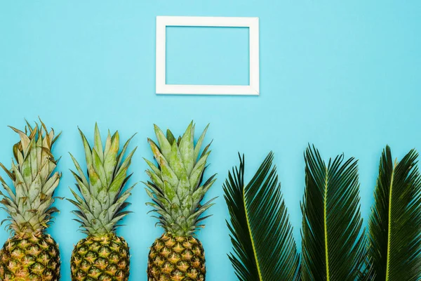 Yeşil Palmiye Yaprakları Olgun Ananasların Üst Görünümü Mavi Arkaplandaki Kare — Stok fotoğraf