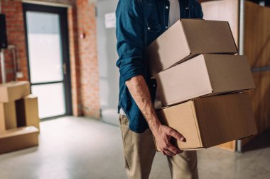 selective focus of businessman holding boxes and moving in new office clipart